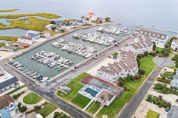 Aerial view of townhouse, marina, pool, and tennis court.