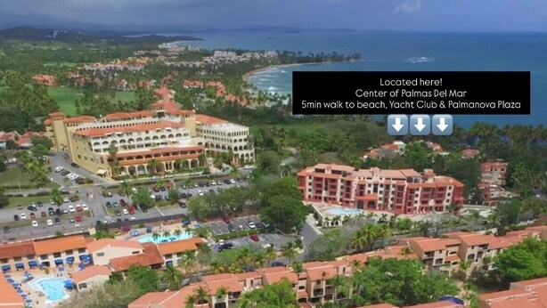 Un hotel frente al mar con varias construcciones, un puerto deportivo y una playa cerca.