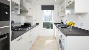 A compact kitchen with a washing machine, a sink, and a window with a view. - 3 Bedroom Large House - Train Station (Derby)