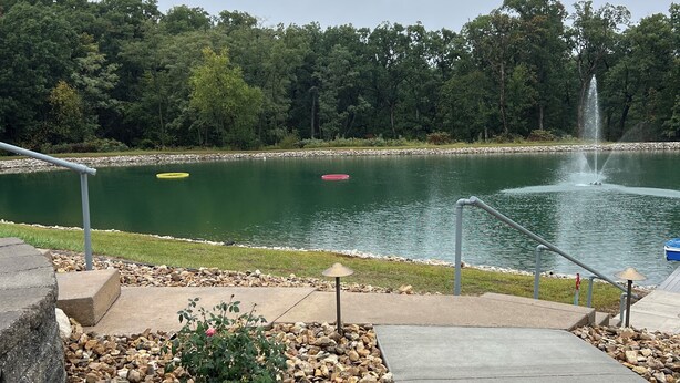 A park with a fountain, a walking path, and a lake.
