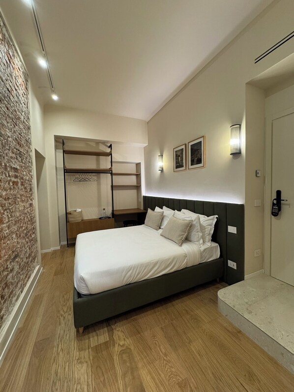 A modern bedroom with a large bed, a wooden wardrobe, and a brick accent wall.