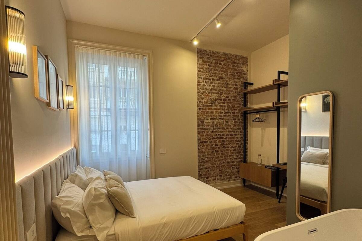 A modern bedroom with a bed, bedside table, and a large bathtub.