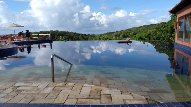 En infinitypool med kristallklart vatten som speglar himlen och den omgivande vegetationen.