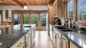 A spacious kitchen with granite countertops, wooden cabinets, and a large island. - Luxury Lake Retreat | Game Room | Winnipesaukee (Gilford)