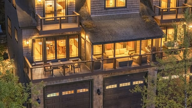 A multi-story house with a balcony, large windows, and a garage. - Luxury Lake Retreat | Game Room | Winnipesaukee (Gilford)