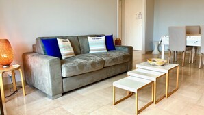 A modern living room with a grey sofa, two cushions, a small table, and a lamp. - Terrasse Felix Faure (Niza)