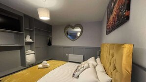 Ein Hotelzimmer mit einem Bett, einem spiegel mit herzförmiger Aussparung, einem Fernseher und einem Bild an der Wand.