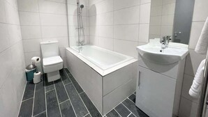 Ein modernes Badezimmer mit Badewanne, Toilette und Waschbecken.