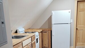 Une cuisine avec des meubles en bois, un réfrigérateur blanc, une cuisinière et un évier.