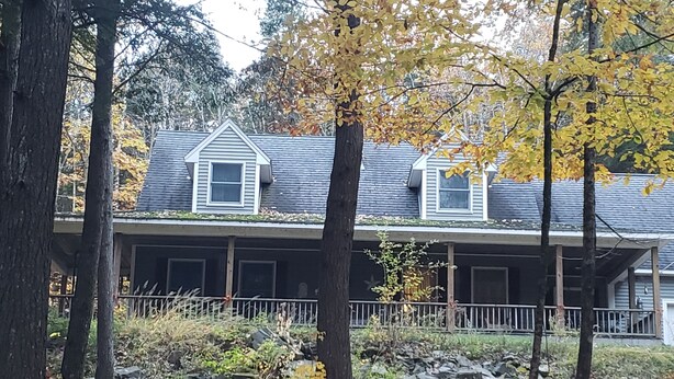 Une maison à deux étages avec un porche et un petit jardin devant.