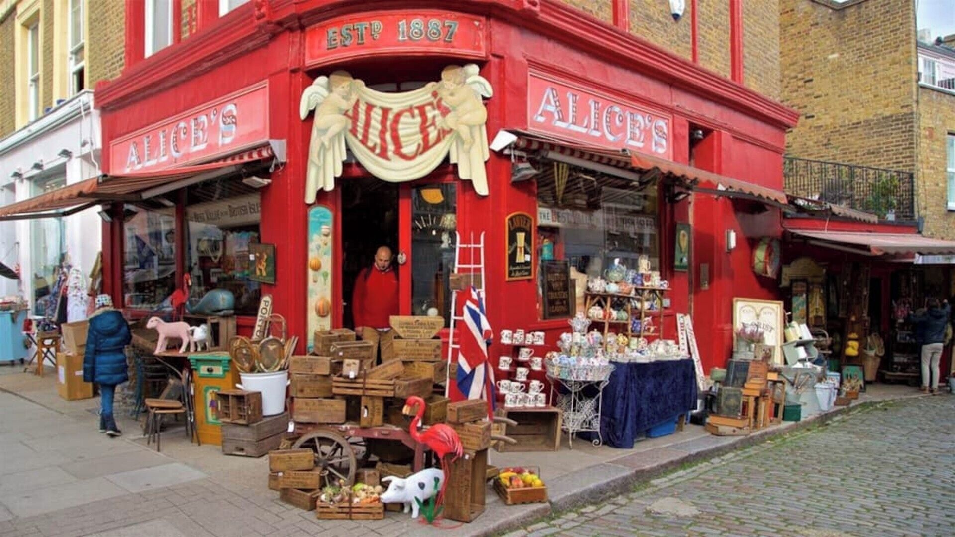 Een rode gevel met de naam 'Alice's', antieke spullen en diverse artikelen uitgestald.