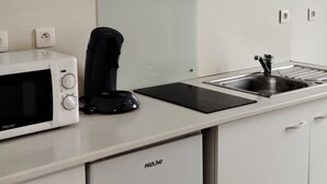 A modern kitchen with white cabinetry, a built-in microwave, a coffee maker, and a stainless steel sink.