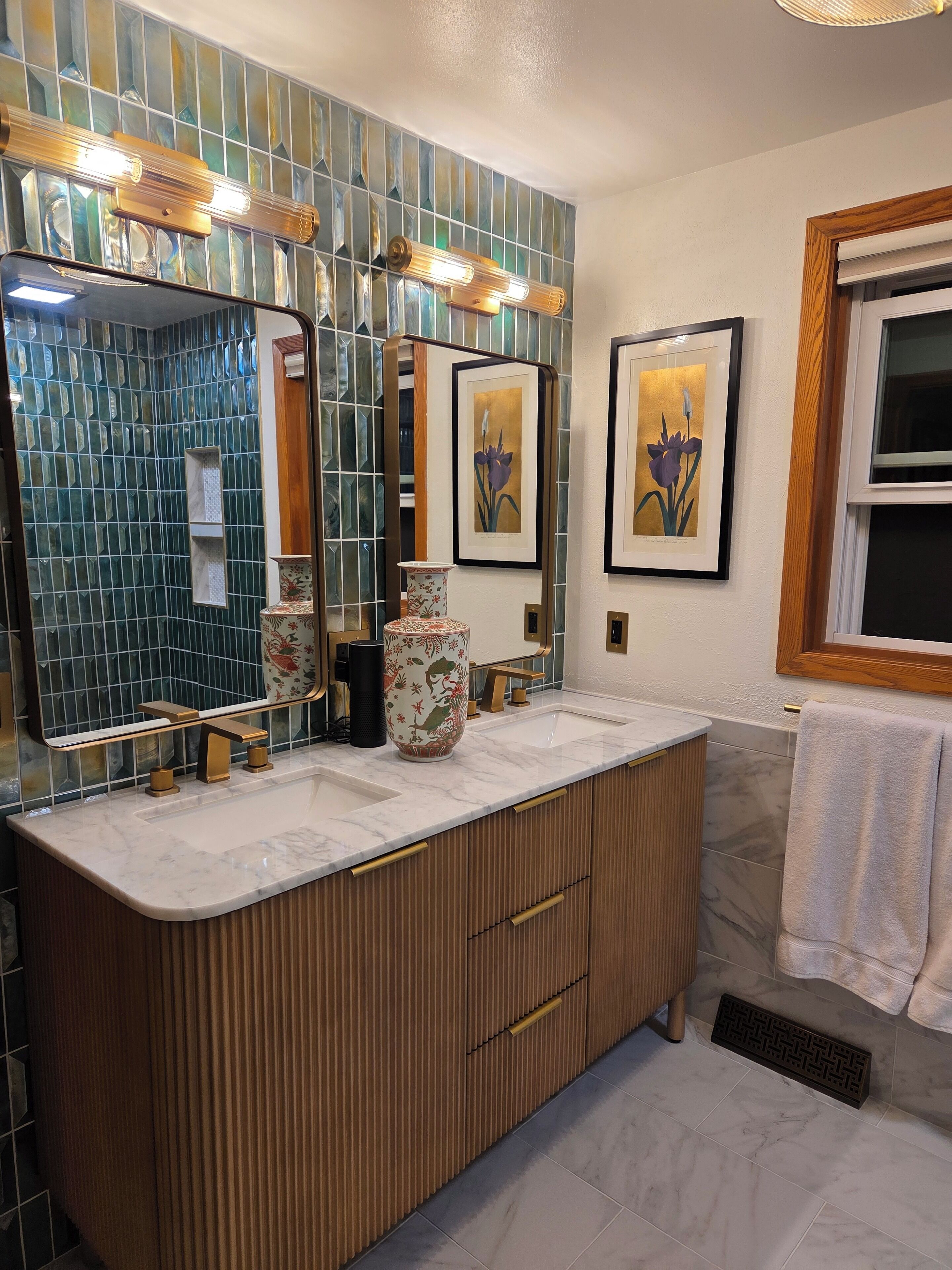 A bathroom with a double sink vanity, a large mirror, and a shower area.