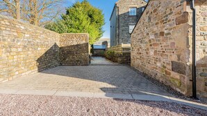 A narrow cobblestone alleyway flanked by stone walls, leading to a stone building with a pitched roof. - The Old Weigh House -Kirkby Lonsdale (Kirkby Lonsdale)