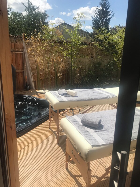 Un espace de bien-être comprenant deux tables de massage, un jacuzzi et un décor en bambou.