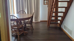 A dining area with a round table and chairs, a staircase, and a hanging light fixture. - Private cabin with resort amenities; kayak, paddleboard, pontoon, great swimming (Pillager)