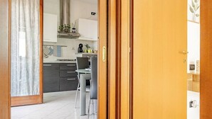 A modern kitchen with a dining area, wooden doors, and a tiled floor. - Venice Home perfect for Venice Airport free parking (Veneto)