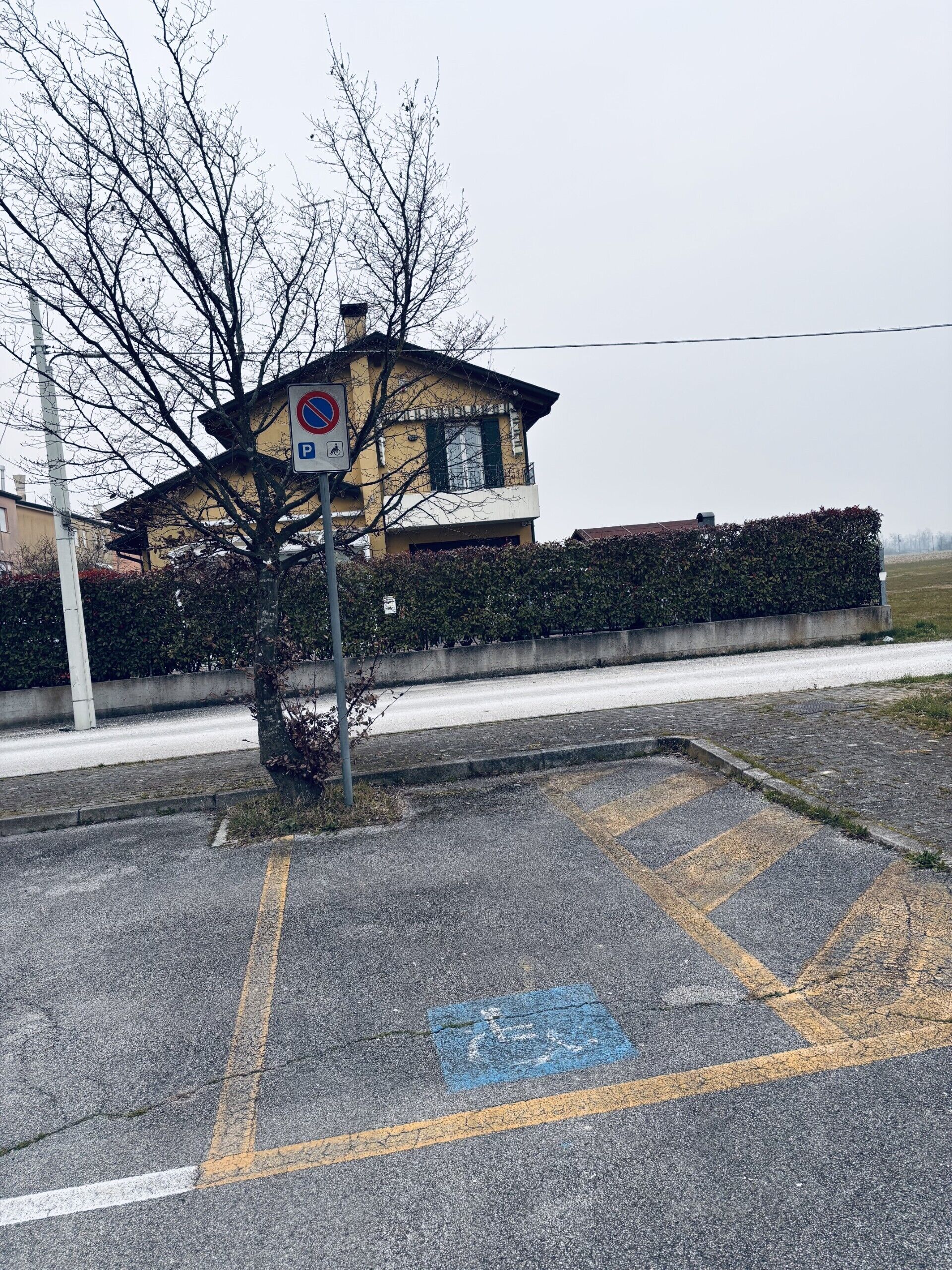 Une zone de stationnement avec un panneau indiquant qu’il est interdit de se garer, une piste cyclable bleue et un bâtiment en arrière-plan.