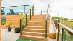 Eine Treppe mit Holzstufen und Metallgeländern, die zu einem Glasbalkon führt.