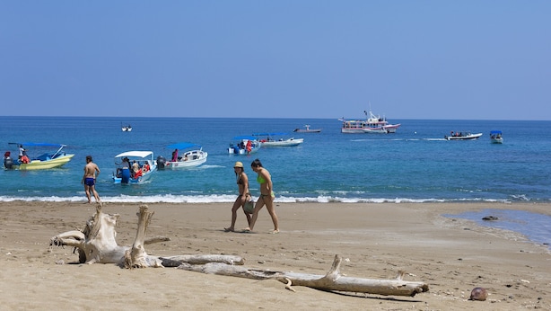 Una playa con barcos y gente.
