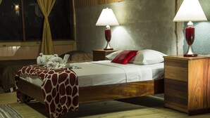 Un dormitorio con una cama de madera, dos lámparas de noche, una mesita de noche, una planta en maceta y una ventana con cortinas.