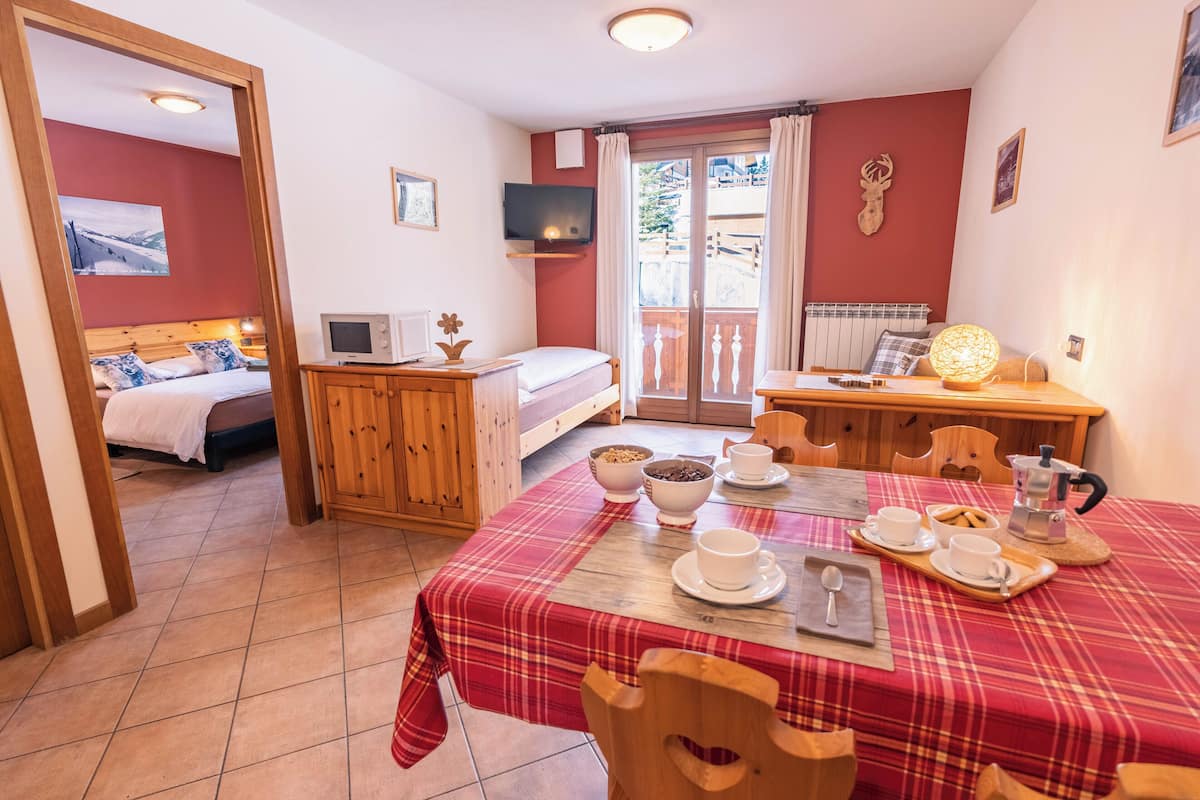 Una habitación acogedora con cama, televisión, mesa de comedor y desayuno, y un balcón con vistas.
