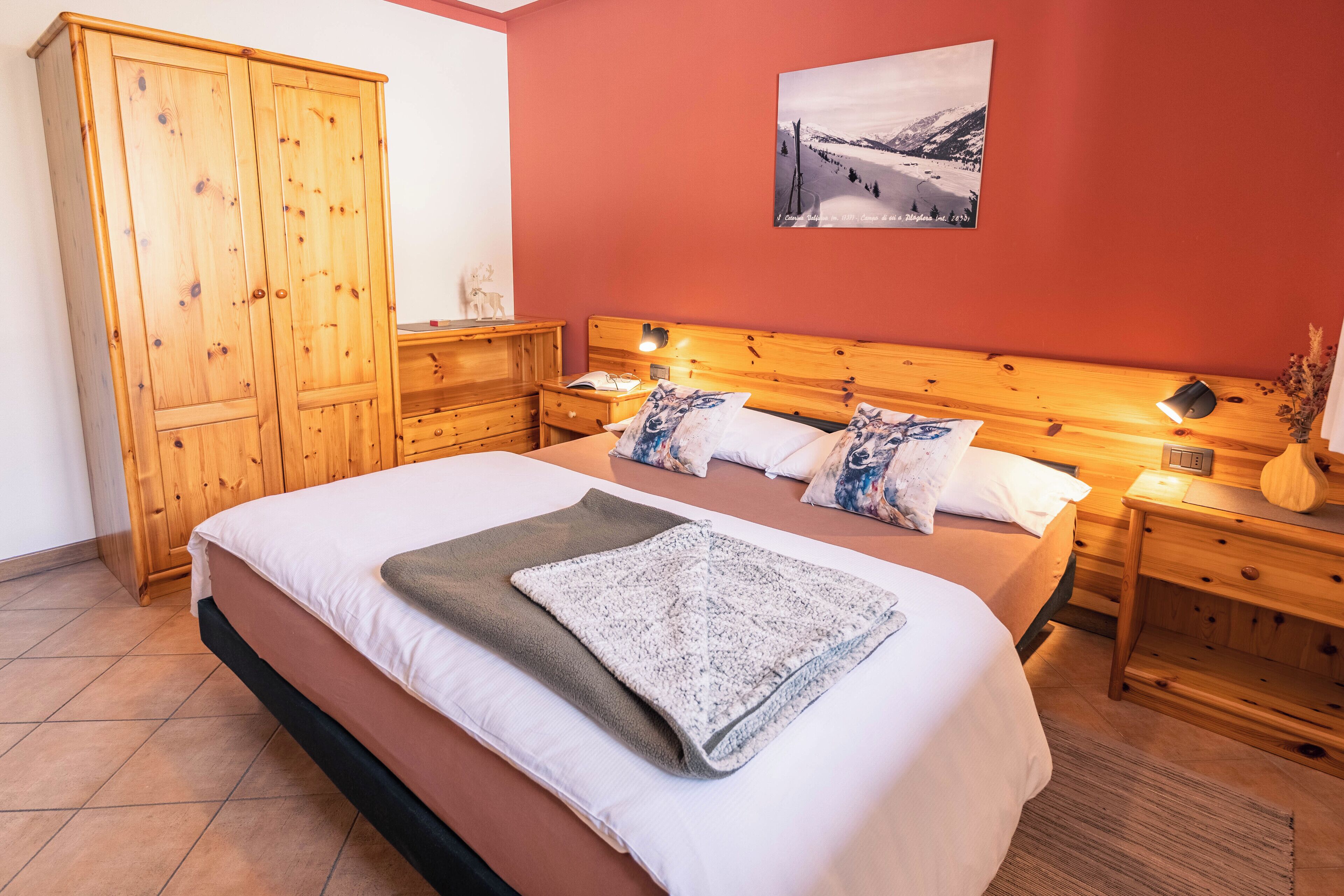 Une chambre à coucher avec un grand lit, des tables de chevet en bois, une armoire en bois et un tableau accroché au mur.