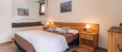 Ein Schlafzimmer mit einem Bett, zwei Nachttischen mit Lampen, einem Holz-Kopfteil, einem roten Teppich und zwei an der Wand befestigten Bildern.