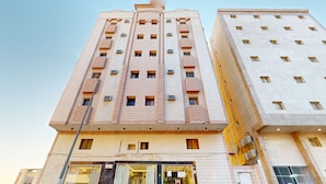 A multi-story building with a modern architectural design, featuring a mix of brick and stone facades, multiple balconies, and a ground-level entrance with glass doors.