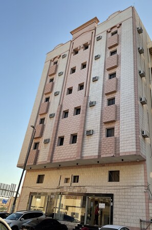 Un edificio a più piani con facciata in mattoni, condizionatori d'aria e un ingresso a livello strada con porte in vetro.