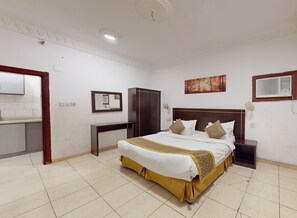 Camera da letto ordinata con un letto grande, un comodino, un armadio, uno specchio e un quadro appeso al muro.