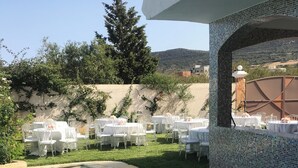 A poolside area with tables and chairs, a tiled wall, and a view of the landscape. - Villa 250 M2 on 800 M (Bizerte)