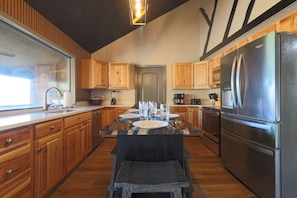 A kitchen with wooden cabinets, a stainless steel refrigerator, a dining table with chairs, and a window. - Endless Views with a Private Indoor Heated Pool (Sevierville)