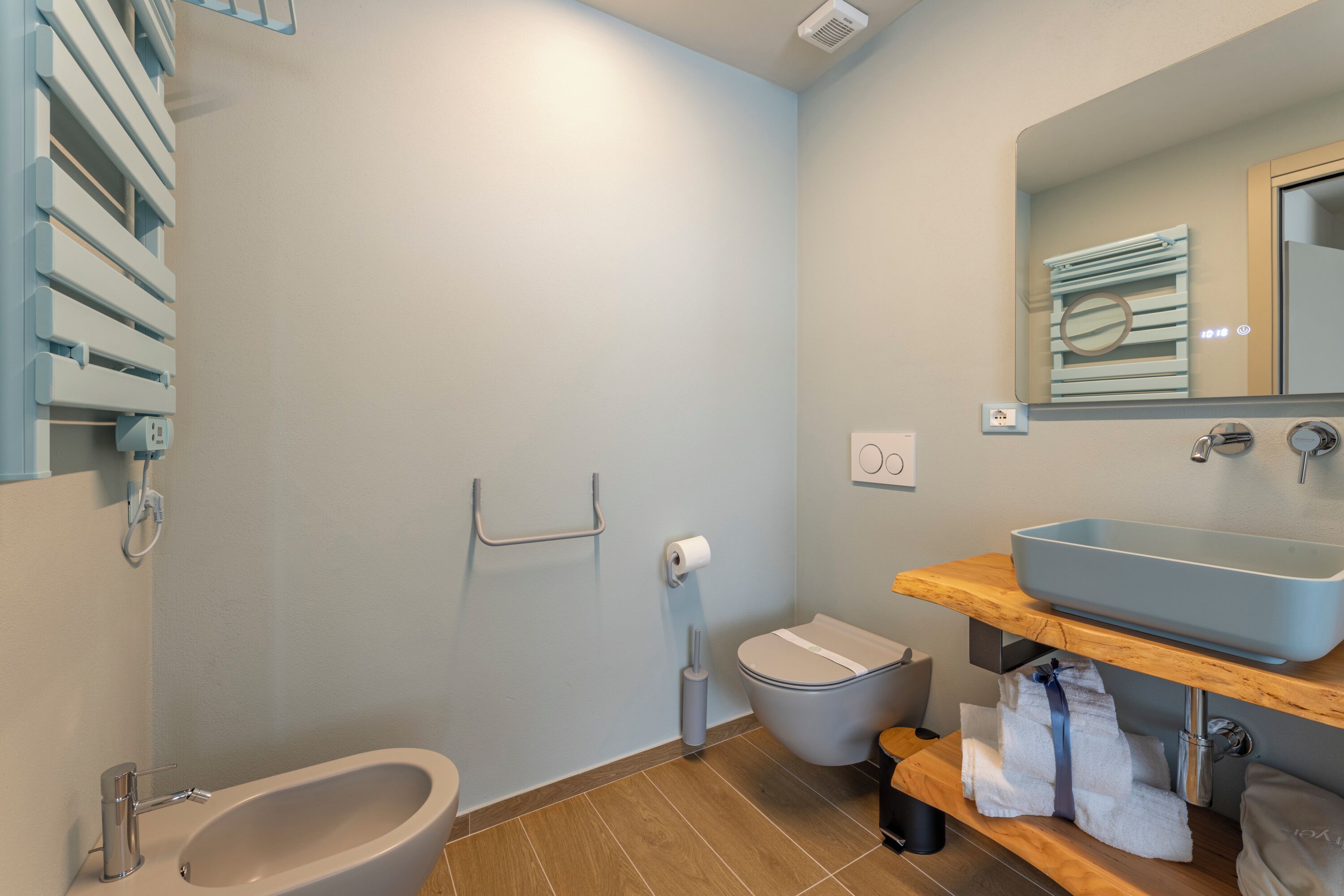 A bathroom with a bidet, toilet, sink, and a towel rack.