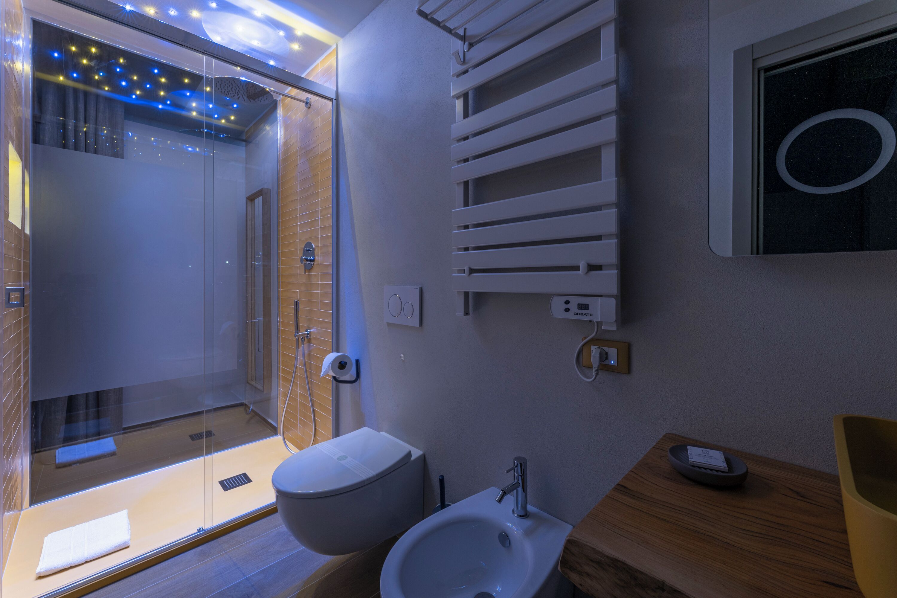 A modern bathroom with a glass shower enclosure, a white sink, and a wooden vanity.