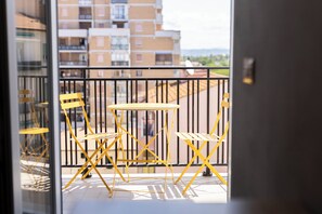 A balcony with yellow chairs and a small table, overlooking a residential area with buildings. - Luci sul Mare (Follonica)