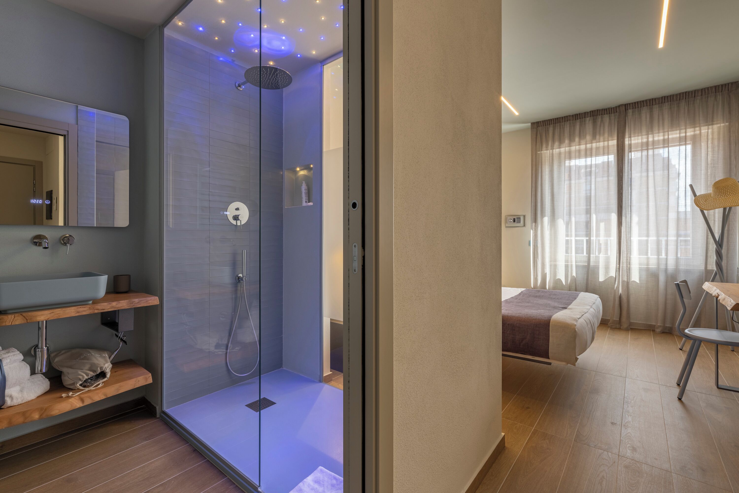 Een moderne badkamer met een glazen douchecabine, een grote spiegel en een houten wastafelmeubel.