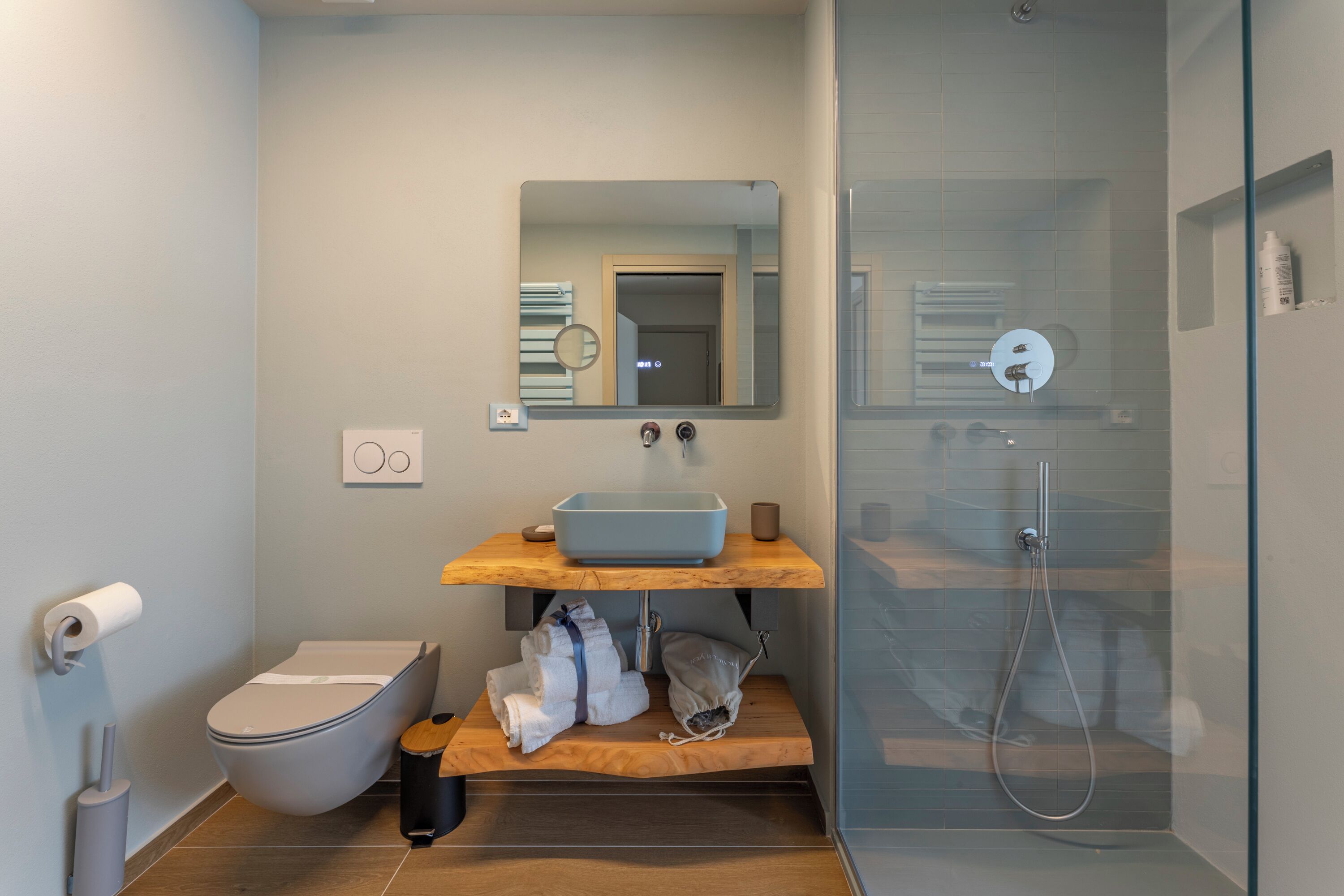 A modern bathroom with a toilet, sink, mirror, and shower.