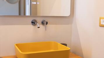 Ein Badezimmer mit einem gelben Waschbecken, einem Spiegel und einer Holzausstattung.
