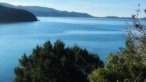 A serene lake with a clear sky, surrounded by hills and dense trees. - Luci sul Mare (Follonica)