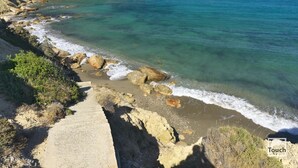 A coastal path with clear blue waters, rocky terrain, and a distant view of the sea. - Paros VIP Pool Villa (Παροικιά)