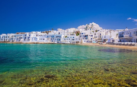 A coastal village with white buildings, clear turquoise sea, and rocky shoreline.