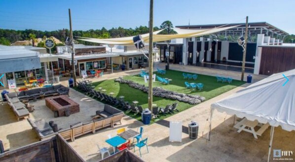 Un espace extérieur aménagé avec une terrasse, des sièges, un petit foyer et une pelouse.