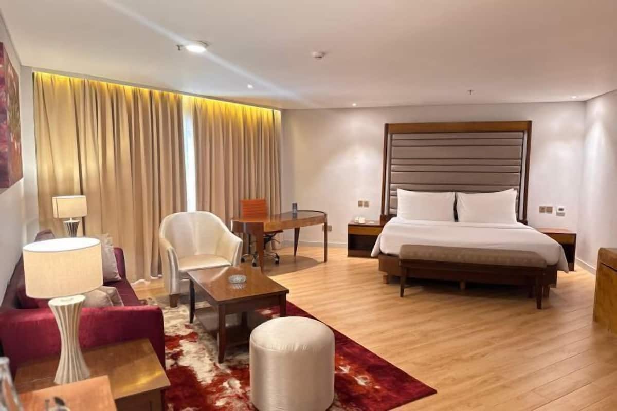 Een hotelkamer met een bed, een bureau, een stoel, een bank en een lamp.