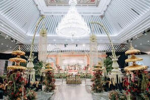 Un espace intérieur doté d’une scène centrale, de lustres et de compositions florales.