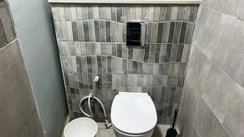 Ein Badezimmer mit Toilette, Bidet und Eimer.