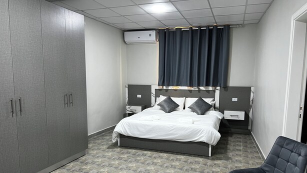 A hotel room with a bed, a chair, a table, and a wardrobe. - Downtown inn  (Madaba)