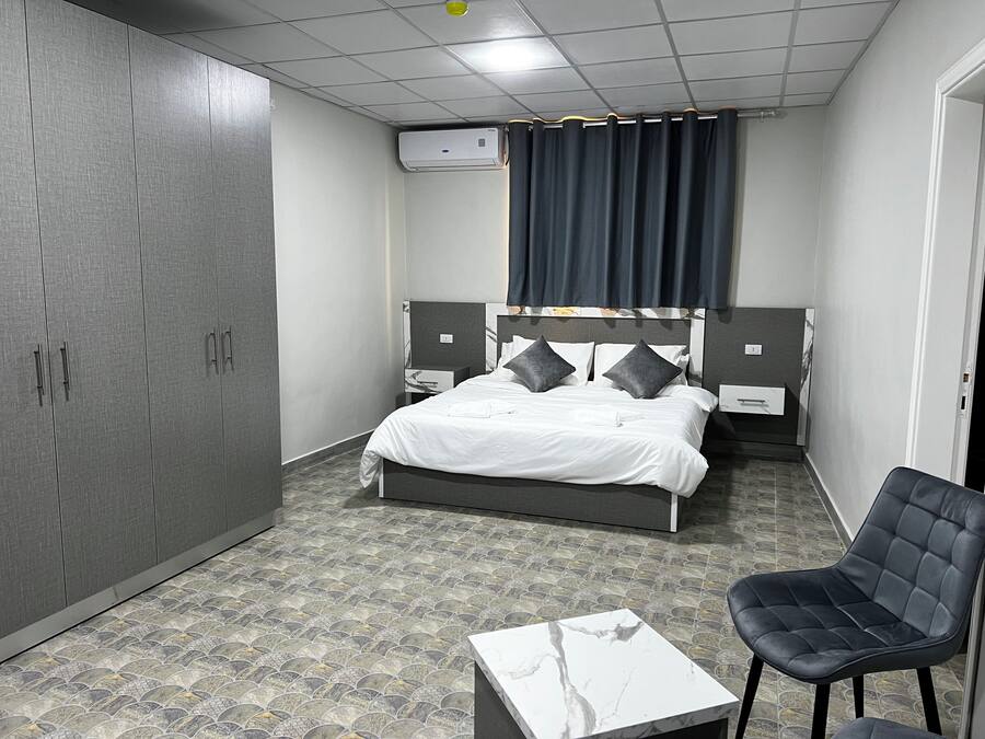 Una habitación de hotel con cama, una silla, una mesa y un armario.