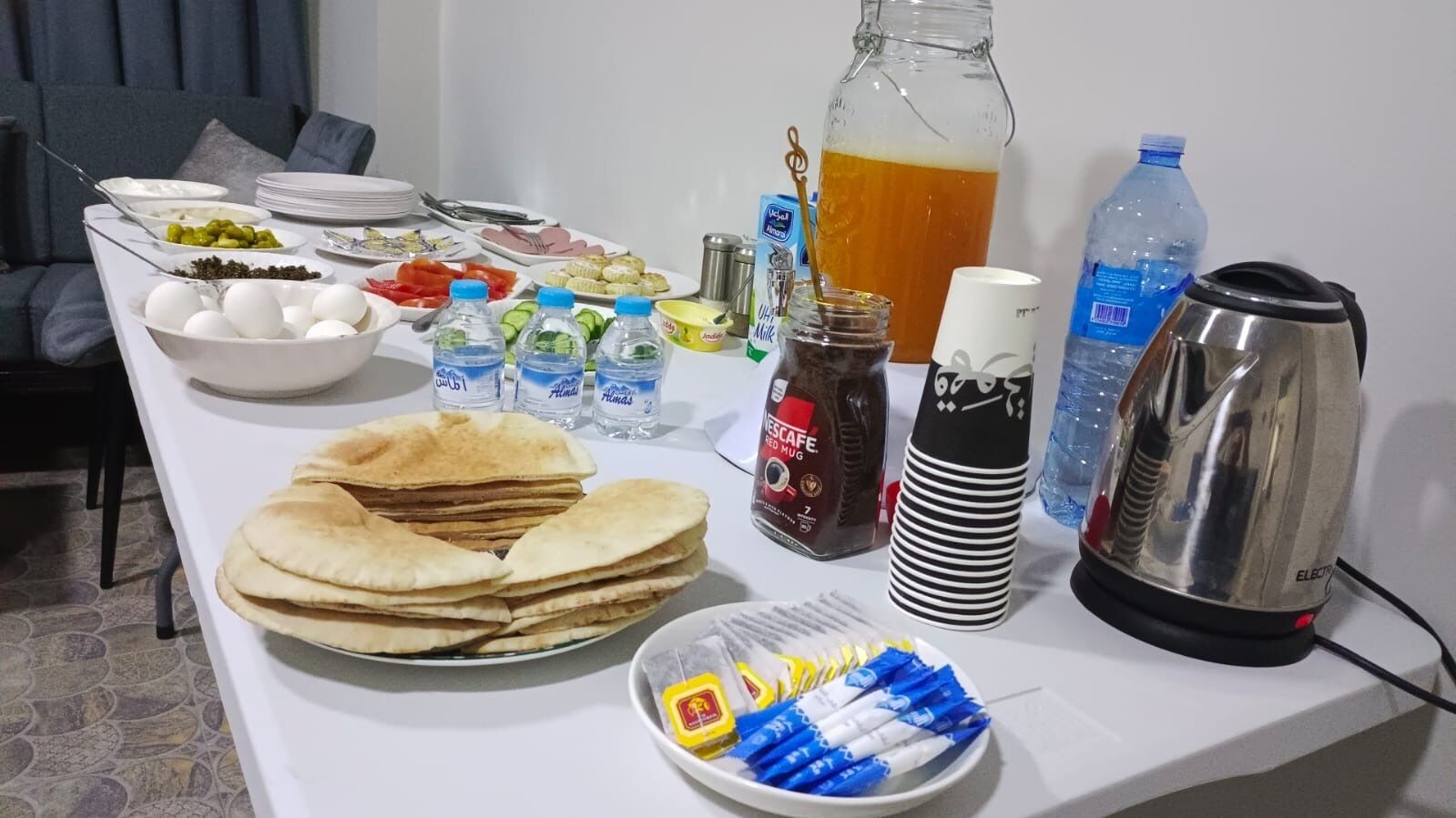 A table with various food items, beverages, and a coffee maker.
