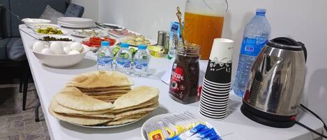 A table with various food items, beverages, and a coffee maker.